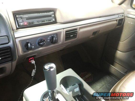 Dashboard and center console of a vehicle, showing the radio, climate controls, gear shifter, and a cup holder