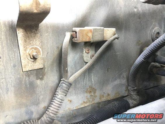 Close-up of a corroded electrical connector with frayed wires in a vehicle's engine bay