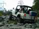 1978 Ford Bronco - Jeep CJ-7 tackling a difficult rocky terrain, with a cooler mounted on the back.