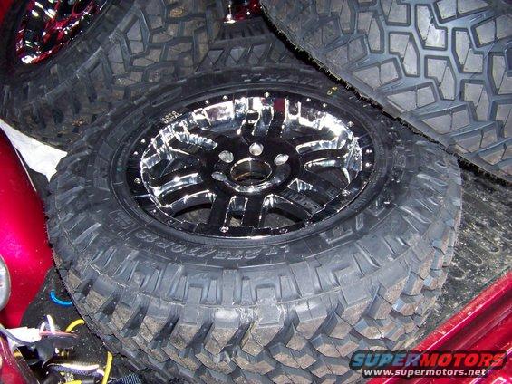 Chrome wheel with aggressive mud tire tread, stacked with other tires