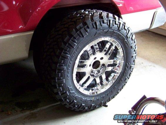 Close-up of a chrome wheel with a knobby tire on a red and tan truck