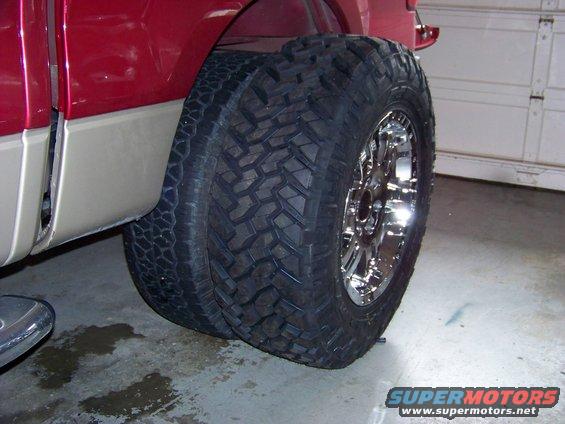 Dual rear tires on a red truck with chrome rims. The tires are large and aggressive