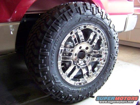 Chrome wheel with aggressive tread tire on red vehicle