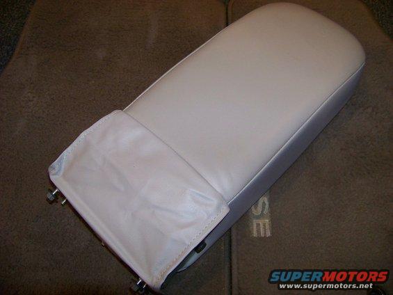 Light-colored armrest with a fabric cover on a brown carpeted surface