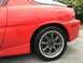 1993 Mazda MX-3 - Rear view of a red 1993 Mazda MX-3 showing the quarter panel, wheel, and spoiler.