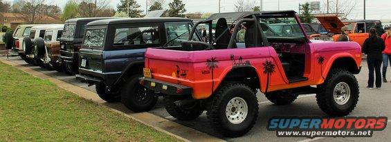 Pink and orange Ford Bronco with palm tree graphics, parked in a line with other SUVs