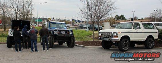 White 1978 Ford Bronco with lifted suspension and aftermarket wheels parked next to a blue Jeep