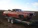 1971 Ford Ranchero - A weathered red pickup truck is being transported on a trailer across a field.