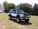 1994 Ford Bronco - This two-tone Ford Bronco is parked on a grassy incline under a clear sky.