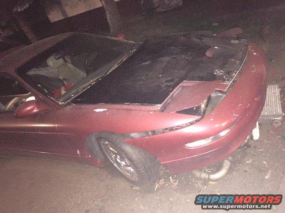red coupe, hood open, front end damaged, headlight missing on passenger side