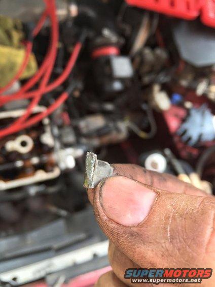 Metal clip held in hand, with engine parts in background