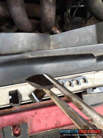 Pliers holding a black engine part near a spark plug wire holder with the number 5 visible