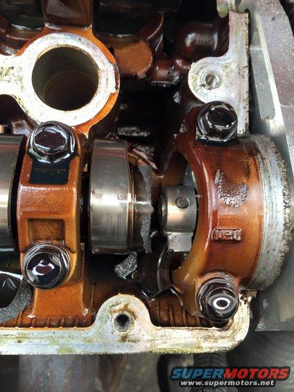 Close-up of damaged engine valve train with broken parts and oil