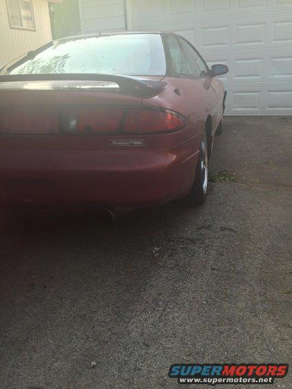 Red 1995 Ford Probe coupe, rear view, parked in driveway. Spoiler on trunk