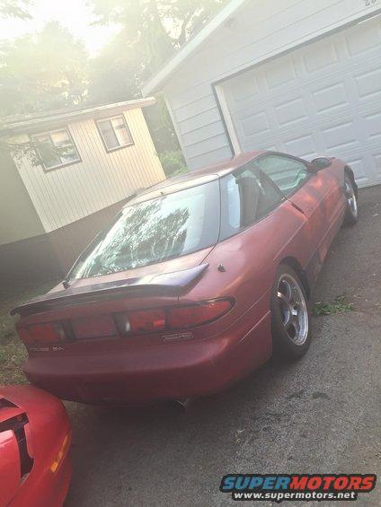 red coupe parked in driveway next to garage, another red car visible on left