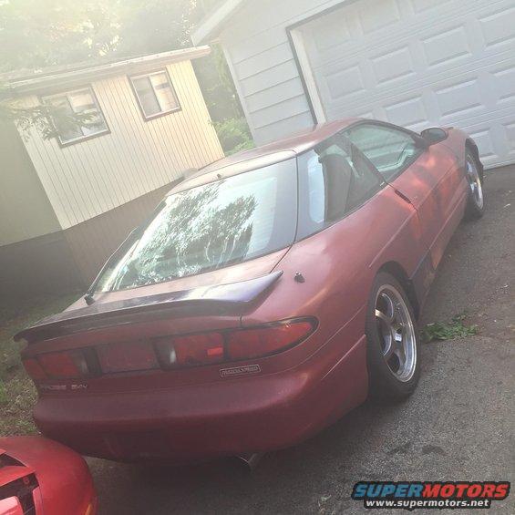 Red 1995 Ford Probe with a spoiler, parked in a driveway