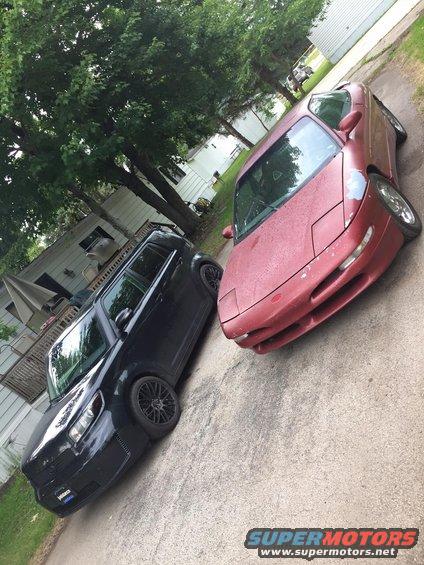 Red sports car with pop-up headlights and faded paint, parked on a driveway