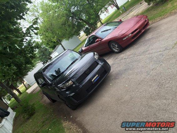 red Ford Probe and black Scion xB parked on driveway