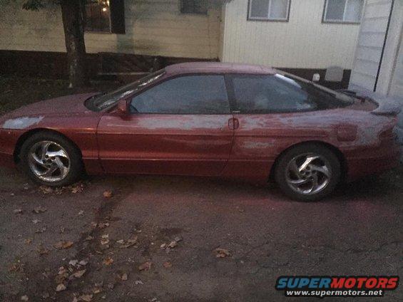 Side view of a red 1995 Ford Probe with primer showing through the paint