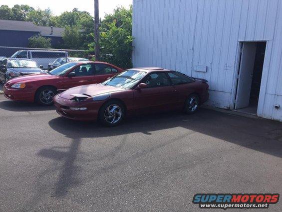 Maroon 1995 Ford Probe parked outside a building, with a red sedan beside it