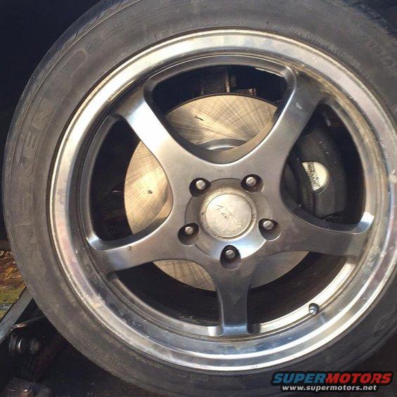 Wheel with five spokes and brake rotor, tire has text