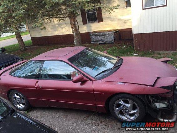 Maroon Ford Probe with pop-up headlights, sunroof, and chrome wheels, parked outdoors