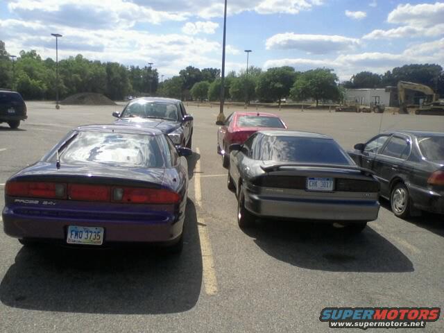 Two Ford Probe cars, one purple and one silver, parked in a lot. The purple one has 'PROBE 2.5' on the rear. The silver one has license plate 'CHK 3017'