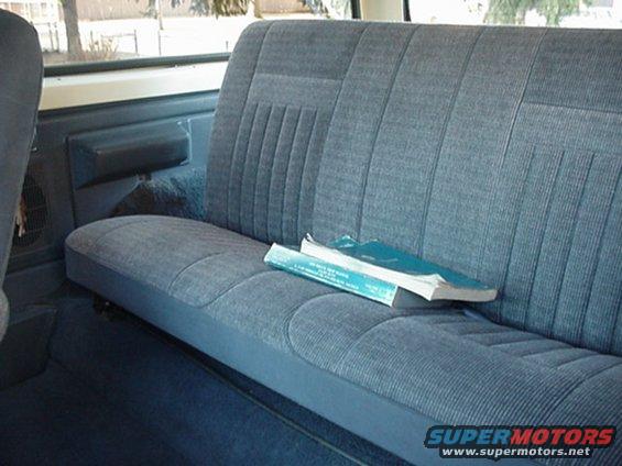 Back seat of a vehicle with two books on it. A SuperMotors logo is in the bottom right
