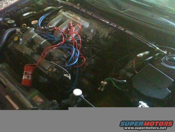 Engine bay with red and blue wires, and a red fire extinguisher