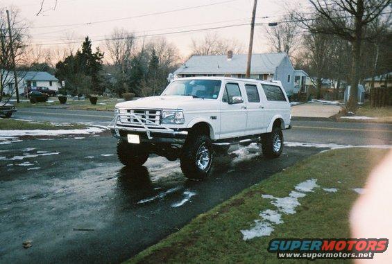 1996 Ford C-250 (Centurion Conversions) lifted with custom front bumper, parked on wet asphalt