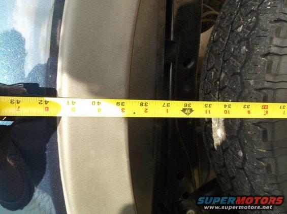 Close-up of a tire and fender well with a yellow measuring tape