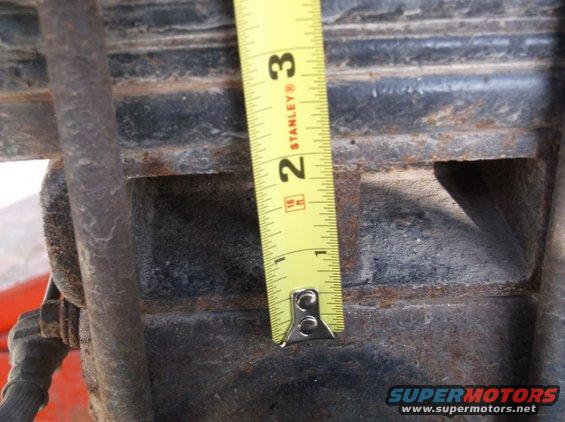 Tape measure against rusty suspension part, showing about 2.5 inches