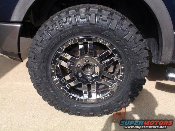 Close-up of a chrome aftermarket wheel with a large off-road tire on a truck