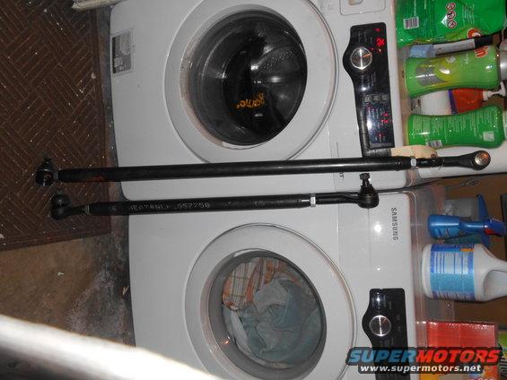 Two tie rod ends, one with part number 557750 visible, resting on washing machines