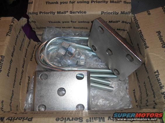 Metal U-bolts, nuts, and square mounting plates inside a Priority Mail box
