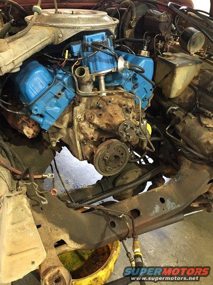 Engine bay of a 1978 Ford Bronco with a blue V8 engine, showing the front of the engine and surrounding components
