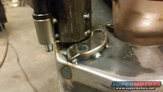 Close-up of a welded metal bracket with a hose clamp attached to a pipe