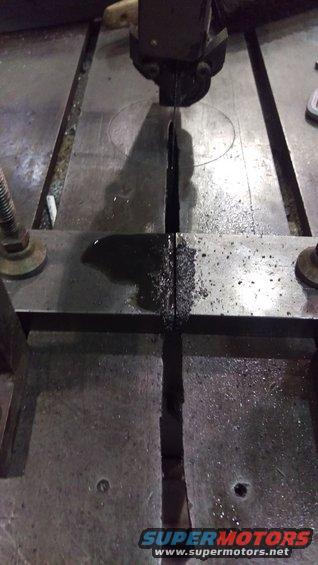 Band saw cutting a metal part with oil and metal shavings on the table