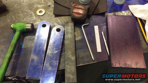 Metal fabrication tools including a hammer, tape measure, and metal pieces