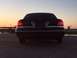 2008 Ford Crown Victoria - The rear of a dark-colored sedan is visible against a sunset sky, with its brake lights on.