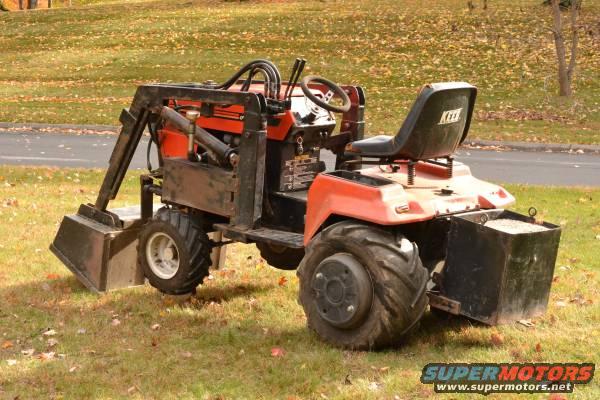 Tractor with front loader and rear weight box parked on grass
