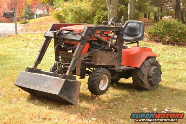Orange tractor with front loader attachment parked on grassy lawn