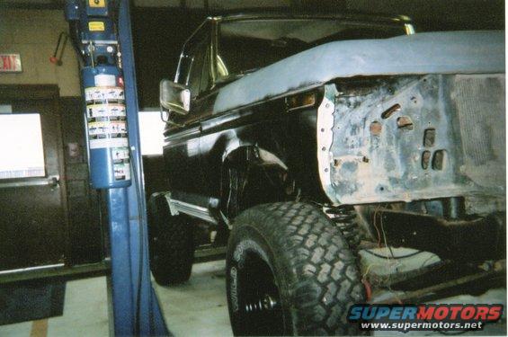 1978 Ford Bronco in a garage, front end partially disassembled, on a lift
