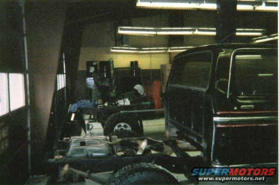 Black Ford Bronco body on a chassis with the fuel tank visible, in a workshop
