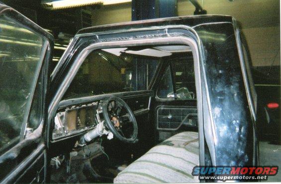 Interior of black pickup truck with torn headliner and aftermarket steering wheel