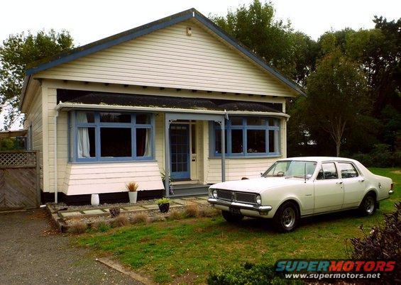 White 1969 Holden Brougham sedan parked on grass in front of a light-colored house with blue window trim