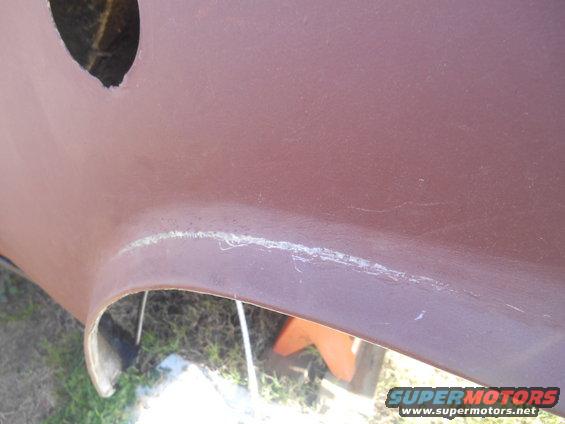 Close-up of a reddish-brown boat hull or vehicle body panel with a repaired seam.