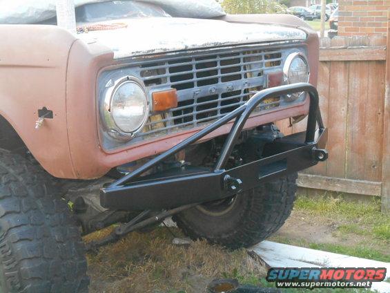 Vintage Ford Bronco front end with custom black bumper, tow hooks, and winch cutout.