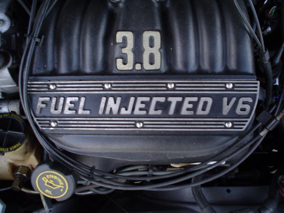 Engine valve cover with "3.8 FUEL INJECTED V6" text. Oil cap visible