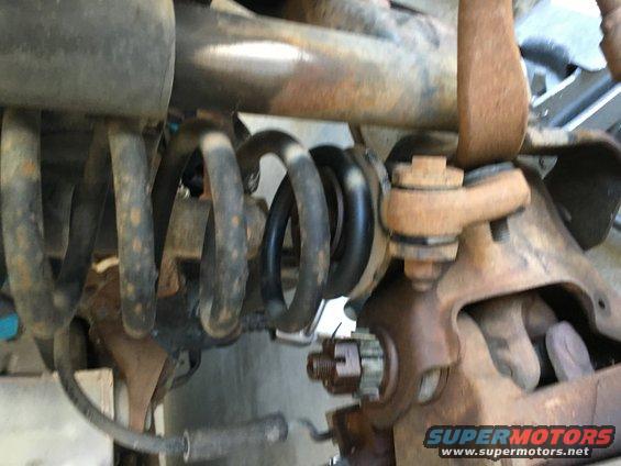 Rusty suspension parts of a 1987 Ford Bronco, including coil spring and ball joint.
